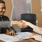 Divorcing couple shaking hands over business settlement documents, representing options like buyout, co-ownership, or selling the business.